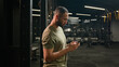 © Yuliia - American Latino ethnic man browsing smartphone serious athlete fit sport guy personal fitness trainer instructor male in gym bodybuilder sportsman using mobile phone looking at camera happy smiling