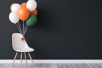 Cheerful celebration setup featuring a white chair adorned with an orange bow, holding vibrant balloons against a dark wall, perfect for festive occasions.