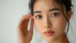 © ThuyTrang - A beauty shot of an Asian model patting eye cream around her eyes, focusing on the delicate eye area, soft natural light, minimalist background, hd quality, emphasizing skincare routine.
