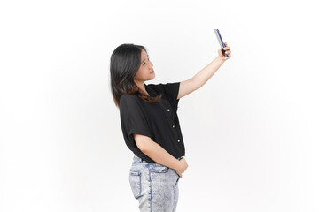 Wall Mural - Young Asian woman taking selfie using smartphone wearing Black t-shirt and jeans isolated on white background