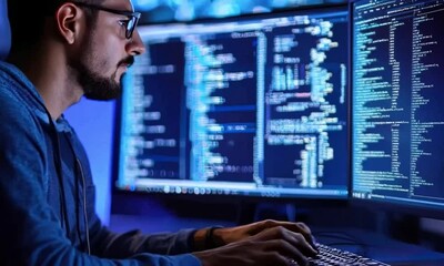 A programmer working on code in a dark room