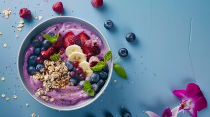 Wall Mural - A beautifully arranged smoothie bowl with vibrant berries, banana slices, granola, and mint leaves against a pastel blue background.