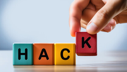 A hand is holding up a block of wood with the letters HACK on it