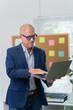 © Tj - handsome business man in an elegant blue suit working with laptop on the table in the office
