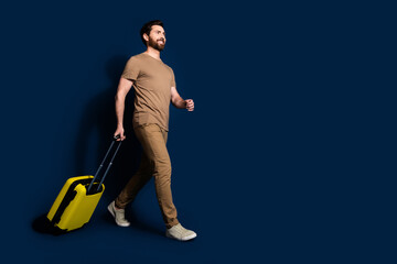 Wall Mural - Photo portrait of mature age brunet bearded funny man in beige t shirt going to his plane with baggage isolated on dark blue color background