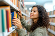 © Pompozzi - Woman browsing bookshelves in library