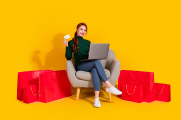 Full length photo of cheerful pretty lady dressed green jumper relaxing chair ordering bargsins modern device empty space isolated yellow color background