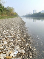 Poster - A sullied riverbank littered with plastic, showing the detrimental effects of pollution on natural water bodies