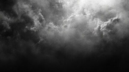 Dramatic black and white image of dense storm clouds, with a small patch of bright light peeking through the center.