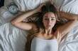© khalid_spk - Attractive woman in bed staring at alarm clock trying to sleep feeling stressed and sleepless