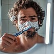 © Big - Man Shaving with Safety Razor: Focused Grooming Ritual in Bathroom Mirror. Face Covered in Foam, Selective Focus on Male Facial Care. Creative Concept for Personal Hygiene Advertising, UI Design, and