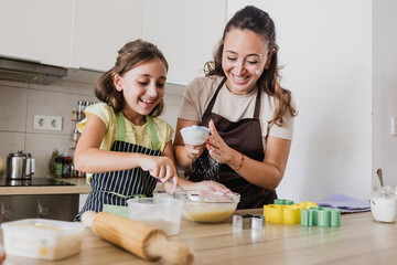 Single mother having fun while baking cookies with daughter