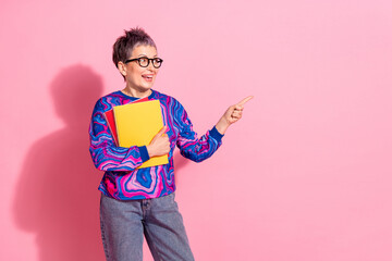 Poster - Photo of attractive senior woman hold copybooks point look empty space dressed blue colorful clothes isolated on pink color background