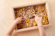 © juliasudnitskaya - Child hand playing natural sensory material in wooden bin. Educational game for development motor skills before preschool and kindergarten.