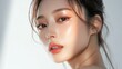 © 69 - Perfectly styled young Asian woman with K-beauty makeup, showcasing her glowing skin on an isolated white background