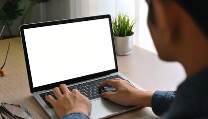 over shoulder shot of a young man using computer laptop in front of an blank white computer screen i