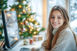 © eshana_blue - Young woman is sitting at her desk, working on her computer with a christmas tree in the background