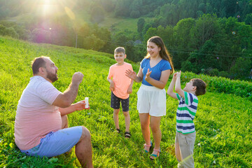 Wall Mural - Father and kids having fun and blowing soap bubbles.