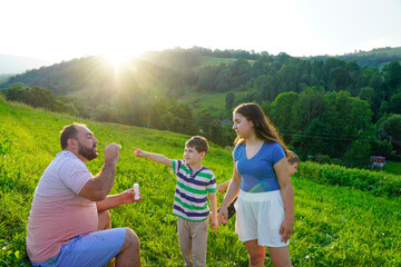 Father and kids having fun and blowing soap bubbles.