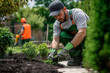 © Andre - Landscaping worker wearing green dungarees and a grey cap, close up