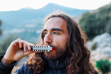 the musician enjoys playing the harmonica while standing on the street.