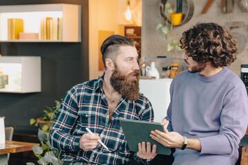 two male designers discussing about a project using a digital tablet in their office