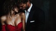 © JoxyAimages - A stylish couple, the man in a black suit and the woman in a red dress, share an intimate and close moment, framed in elegant and moody dark tones.