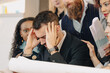 © Alessandro Grandini - Businessman having headache at work while team is having meeting