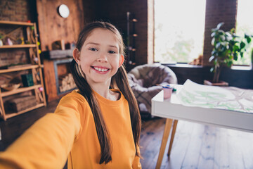 Wall Mural - Photo portrait of charming little girl take selfie photo dressed orange garment spend pastime spacious house indoors room