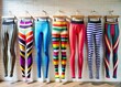 © Adisorn - Fashionable leggings with colorful stripes and trendy designs hang on a minimalist studio wall, creating a chic and modern athletic wear display.