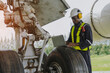 © eakarat - Mechanics inspect the engines of a large plane before takeoff at a summer airport.