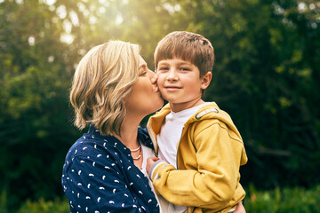 Canvas Print - Mother, happy son and outdoor portrait with kiss, vacation and support in relationship connection. Boy, mom and together for security embrace in countryside, trust and affection in England for peace