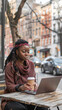 © liliyabatyrova - A woman with dreadlocks is sitting at a table with a laptop and a cup of coffee