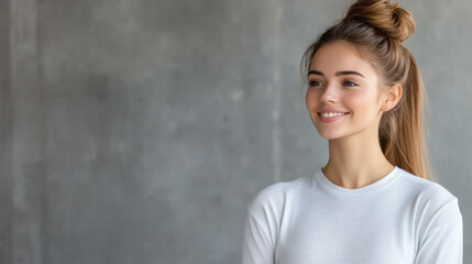 Wall Mural - Portrait of a cheerful young woman wearing a white shirt, smiling and looking away in a minimalist indoor setting.