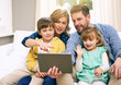 © peopleimages.com - Family, sofa and tablet in house for video call, streaming and movie with internet, website and wave. Parents, tech and children in living room for film, relax and playing game on weekend on couch