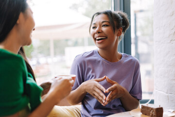 Two young women having fun chatting and drinking coffee in cafe