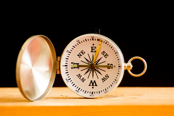 Compass on a wooden table against a black background