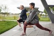© Seventyfour - Side view of fit senior woman holding static lunge position strengthening leg muscles while working out together with male partner at windy city park, copy space