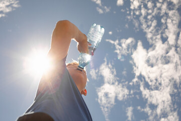 Active child drinking from bottle of water outdoors 