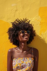 Poster - A woman stands in front of a bright yellow wall, wearing trendy sunglasses