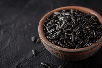 Wall Mural - Black sunflower seeds in black bowl top view