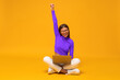 © Damir Khabirov - Winner. Excited happy business woman sitting on floor with laptop, shouting yes, isolated on yellow