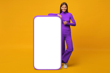 Wall Mural - Happy young woman standing and showing blank screen of huge phone, mock up for your app