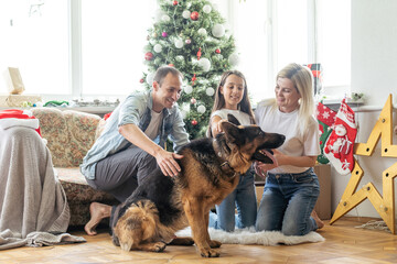 Wall Mural - happy family and cute dog having fun at christmas tree. atmospheric emotional moments. merry christmas and happy new year concept.