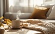 © Alena - A minimalist Scandinavian living room with soft autumn light, oversized knit throw blanket, warm neutral tones, ceramic mug of steaming tea on a wooden coffee table, subtle fall decor