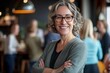 © Vooglo.com - A confident professional woman in her 50s, smiling and standing with her arms crossed