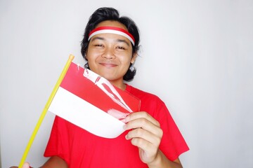 Portrait of an Indonesian man with long hair with a headband and red shirt celebrating Indonesian Independence Day with high nationalism on an isolated white background