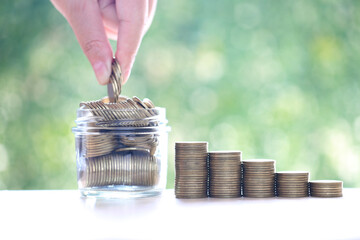 Wall Mural - Saving money for prepare in future concept, Stack of coins money and the glass bottle on natural green background