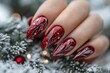 © Gatherina - Woman hand with red christmas glitter nails holding snow covered pine branch