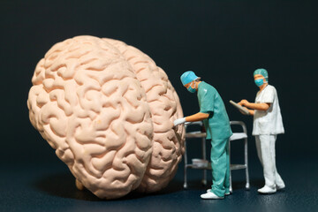 Wall Mural - Miniature people of surgeons examining a large brain model. symbolizing the complexities of neuroscience and medical research